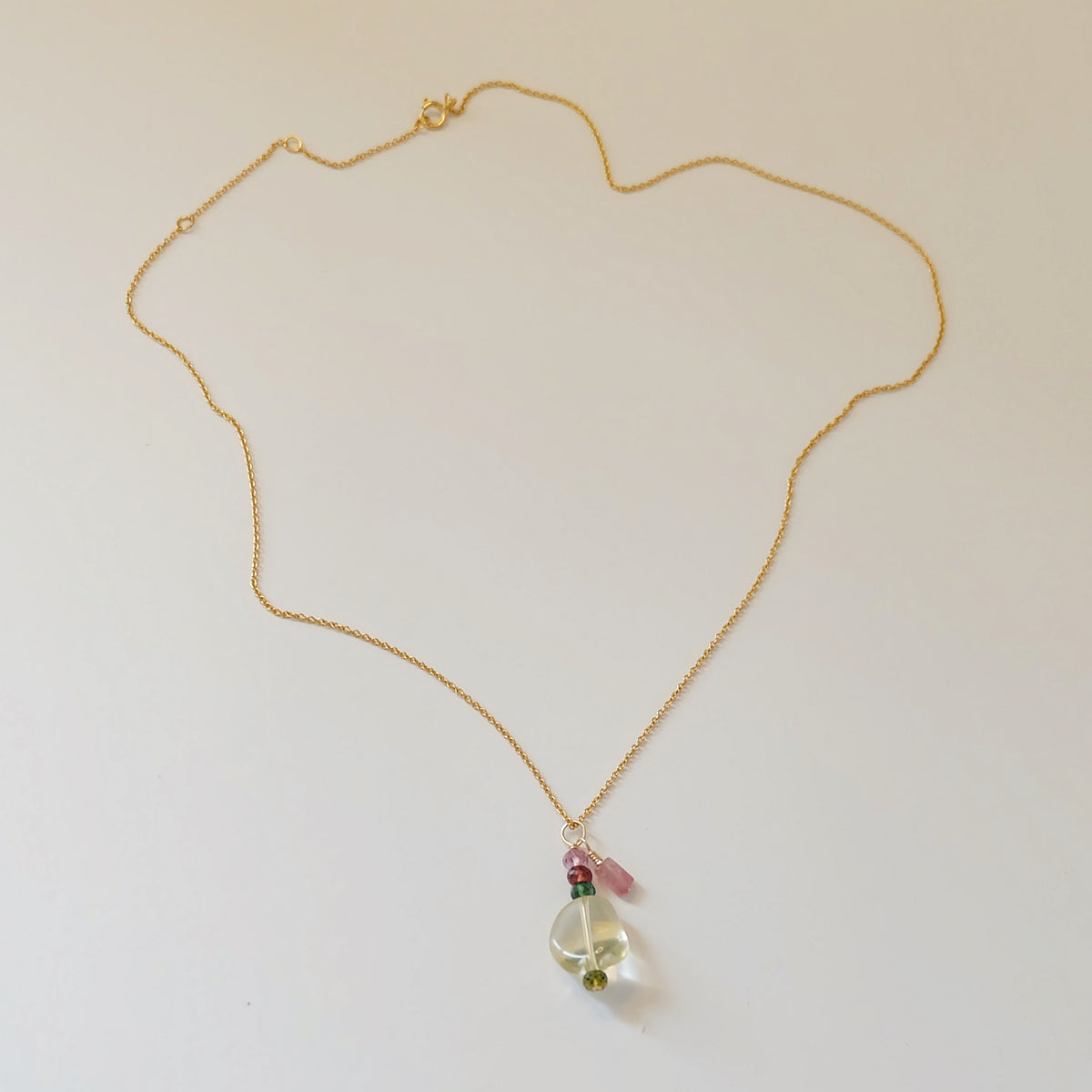 Close-up of green amethyst and tourmaline charms on a dainty gold-filled necklace