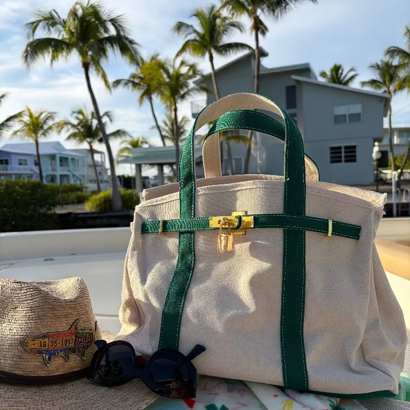 Green Boatkin bag on a boat deck with palm trees and houses in the background