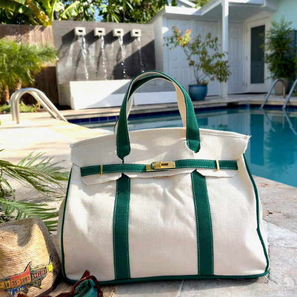 Green Boatkin tote bag by a pool with a house and palm trees in the background.