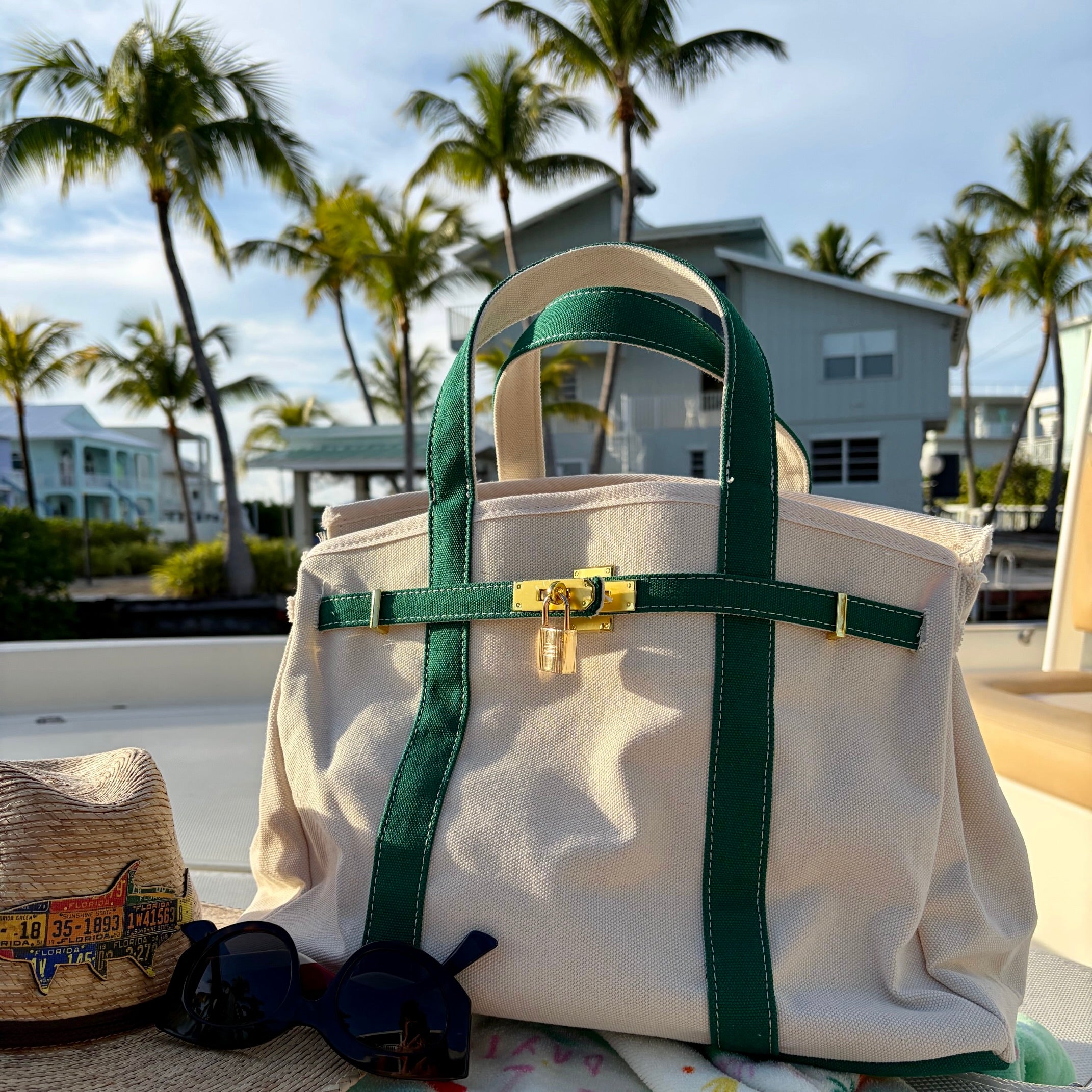 Green Boatkin tote bag on a boat deck with palm trees and homes in the background