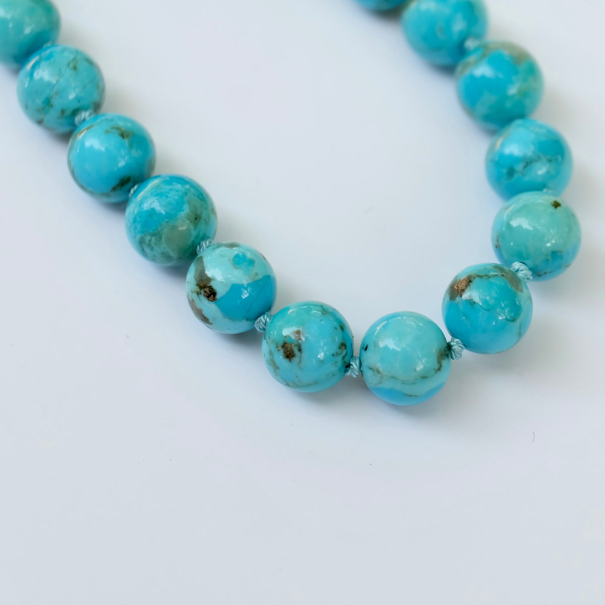 Close-up of Kingman turquoise beads hand-knotted on aqua blue silk
