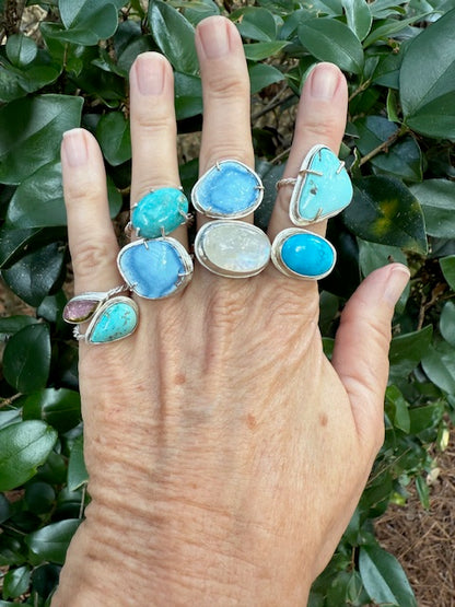 Hand wearing multiple rings including a Golden Hills Turquoise Ring in 14k gold