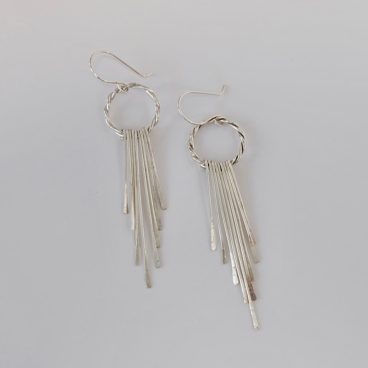 Elegant silver fringe earrings featuring delicate strands that sway gracefully, adding a touch of sophistication to any outfit.
