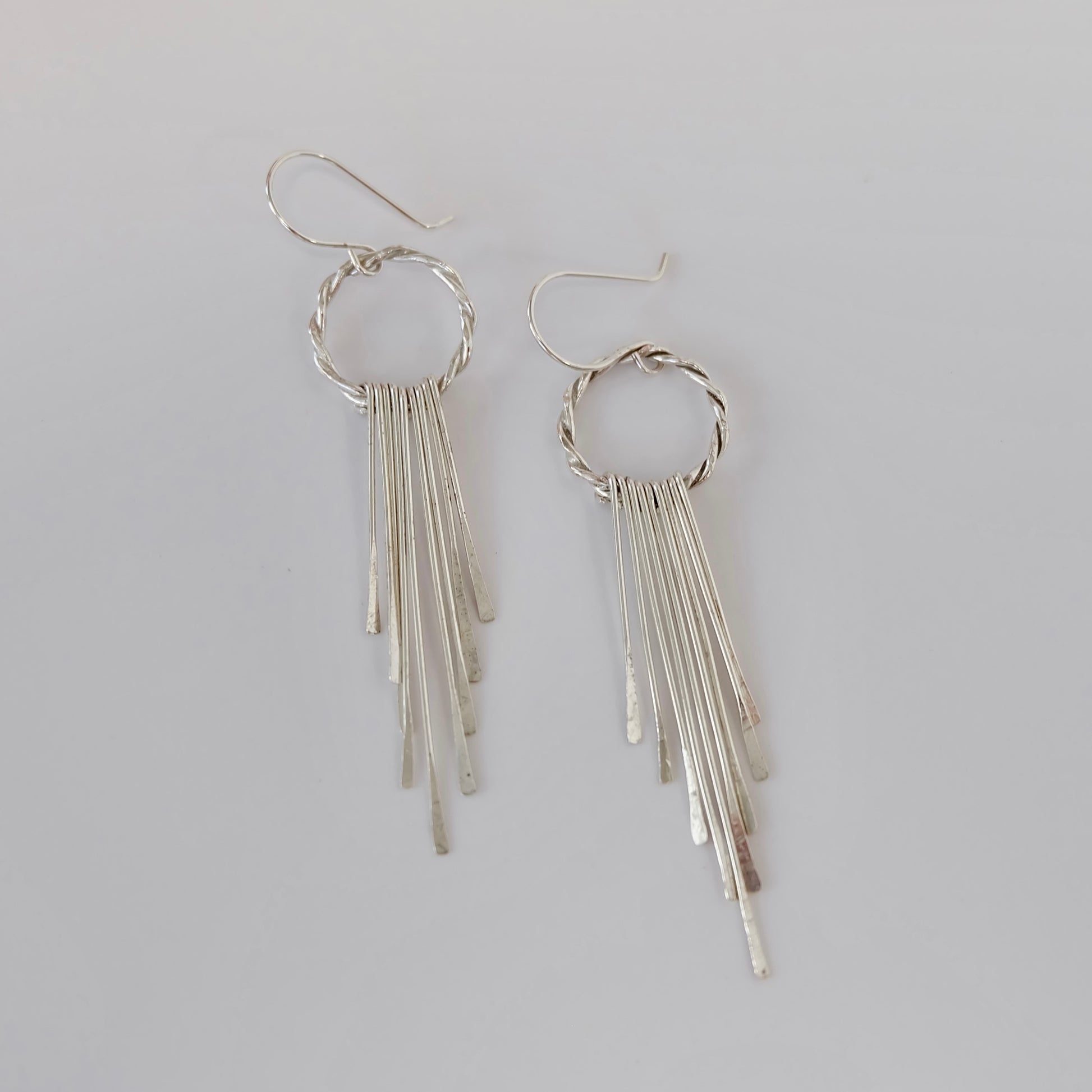 Elegant silver fringe earrings featuring delicate strands that sway gracefully, adding a touch of sophistication to any outfit.
