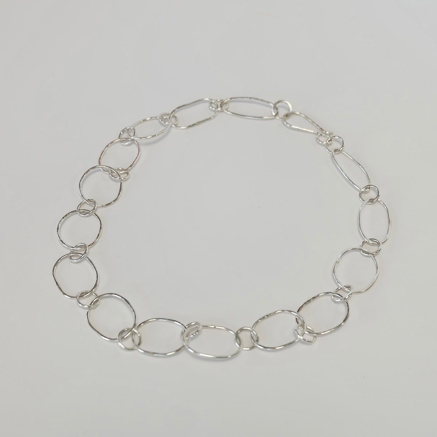 A delicate silver link necklace featuring interlocking links, showcasing elegance and simplicity in design.