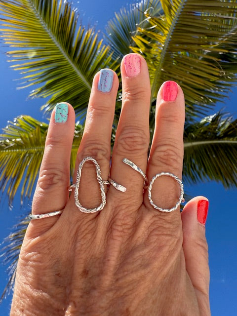 A woman wearing multiple handmade sterling silver rings showcasing their craftsmanship and shine.