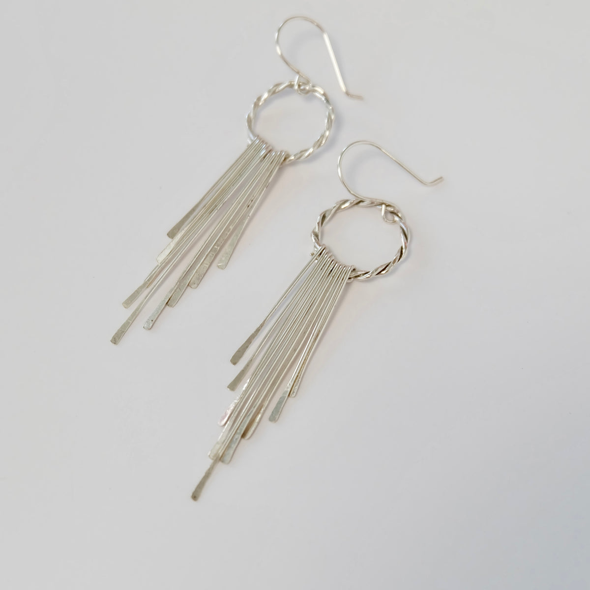 Handmade sterling silver tassel earrings laid flat