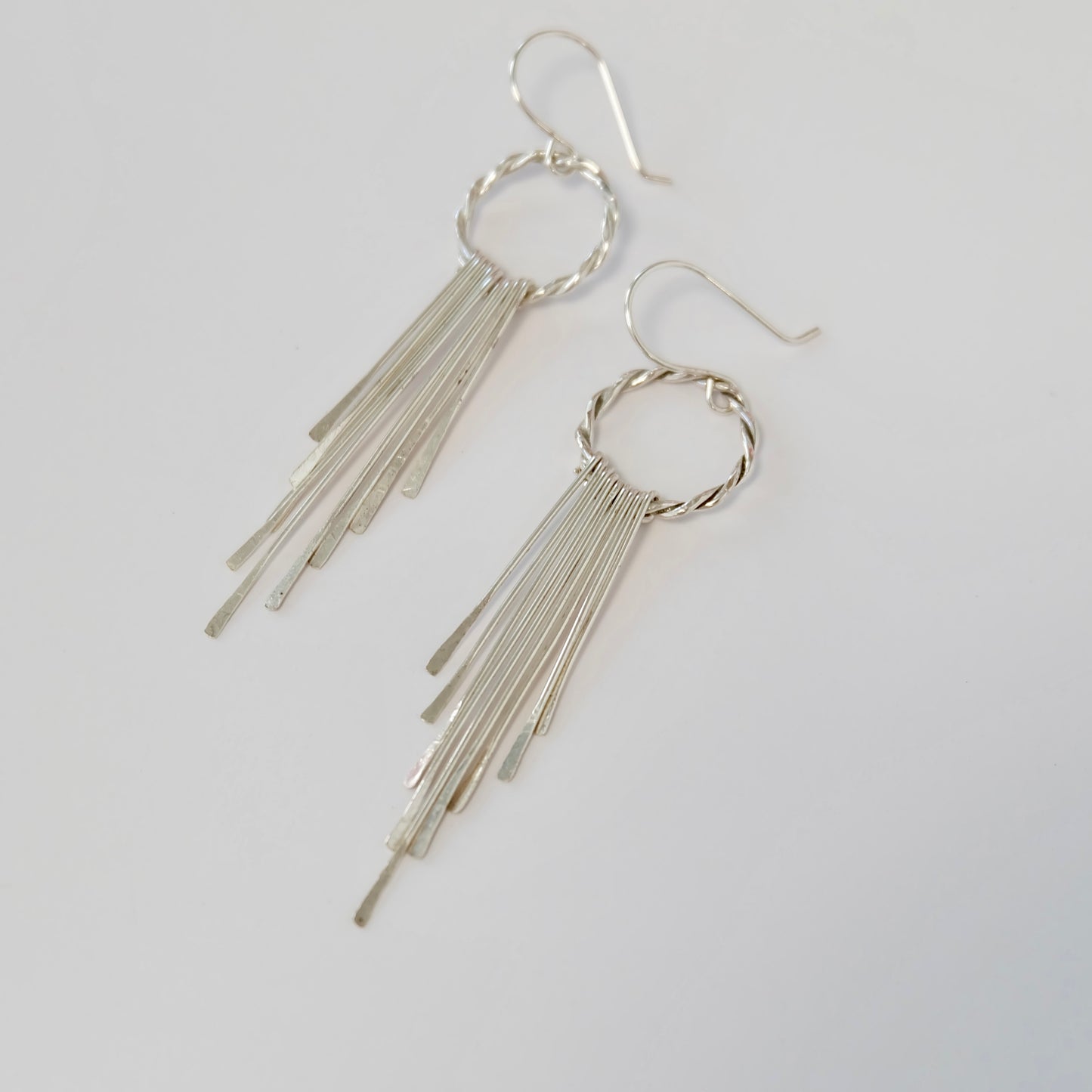 Display of handmade sterling silver tassel earrings on flat surface
