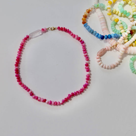 Hot pink opal beaded candy necklace with pink beads and bracelets with colorful beads on a light gray background