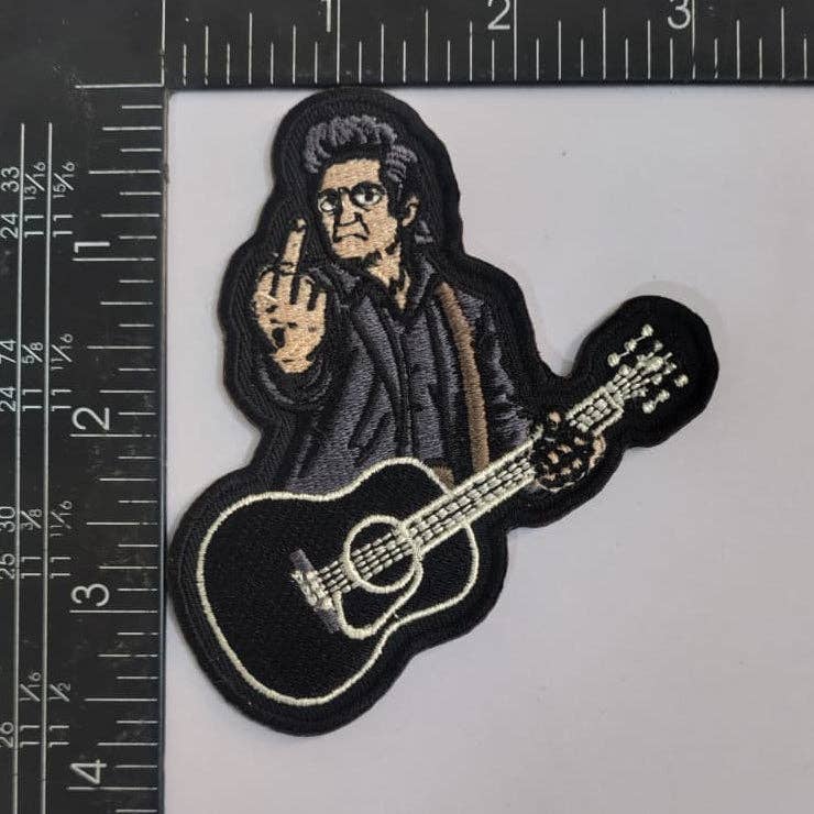 Embroidered patch of a Johnny Cash with a guitar, next to a ruler for scale.