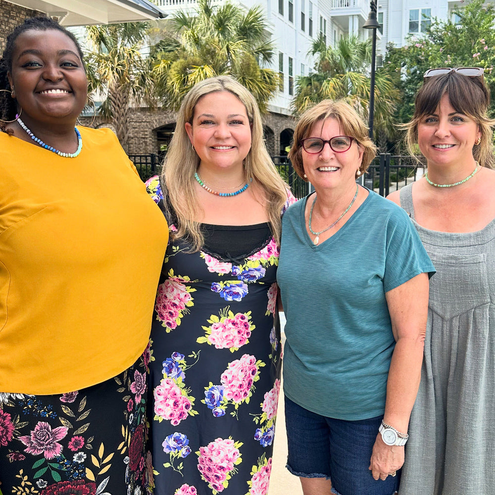 A group of smiling friends enjoying a private jewelry making craft class for a Key West bachelorette party.