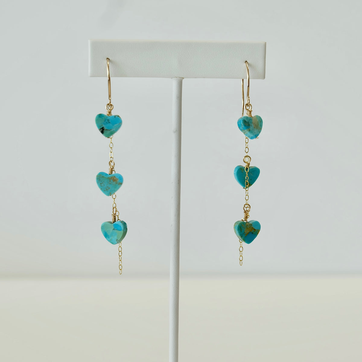 Kingman turquoise heart dangle earrings on a white background