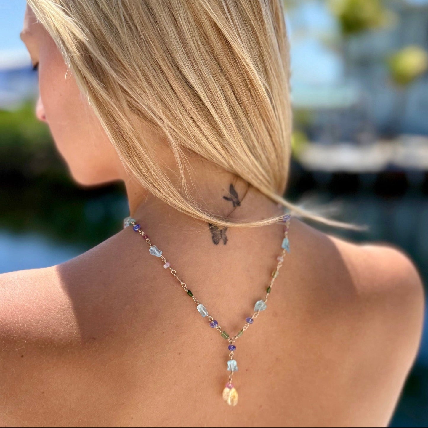 A woman wears a colorful gemstone lariat necklace, highlighting its vibrant hues and elegant design.