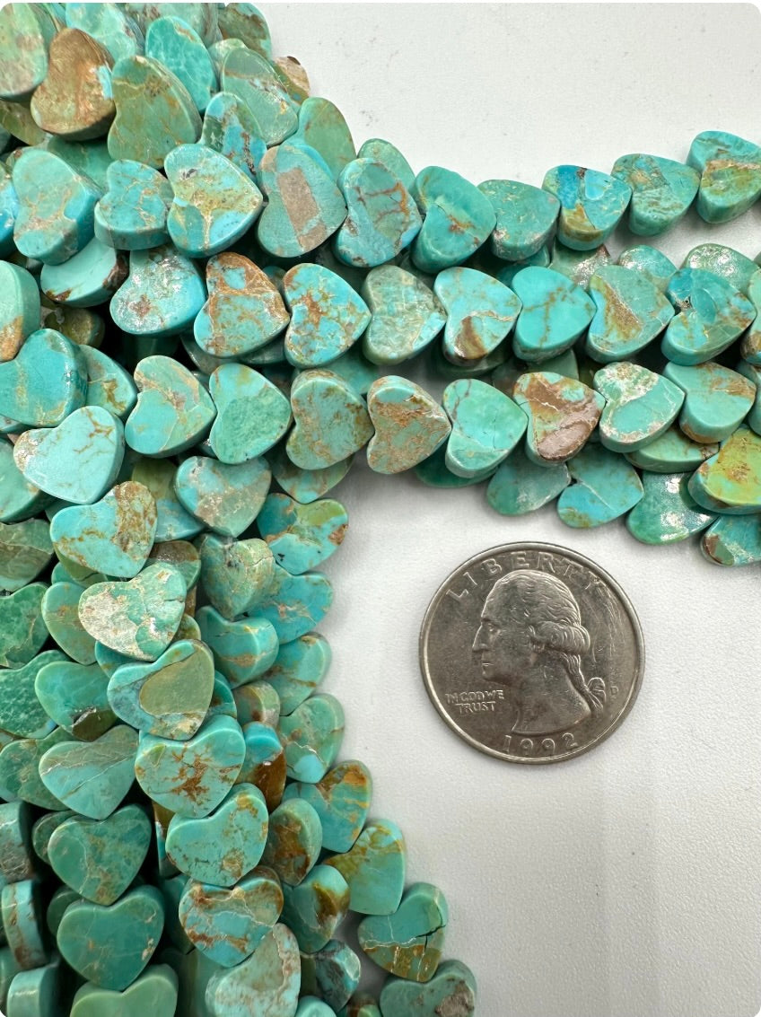 Lime-green turquoise heart-shaped beads with a quarter for scale on a white background