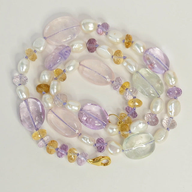 Close-up of faceted rose quartz, green amethyst, citrine, and freshwater pearls on a mixed gemstone candy necklace