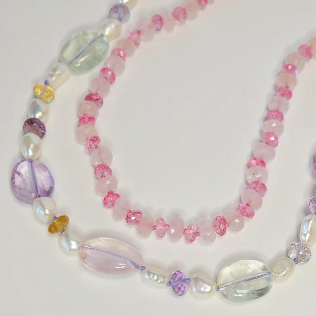 Flat lay of mixed gemstone beaded candy necklaces with rose quartz, amethyst, citrine, pearls, and a 14K gold-filled clasp on purple silk