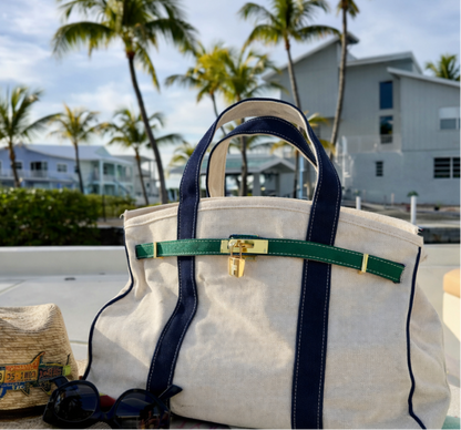 Navy and green Boatkin bag on a boat with palm trees and houses in the background.