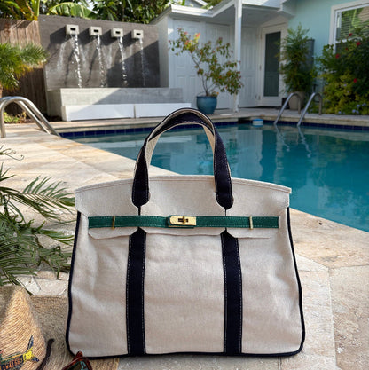 Navy and green Boatkin tote bag by a pool with a house and palm trees in the background.