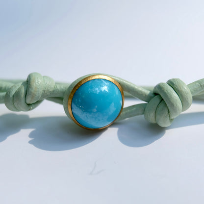 Necklace with a button and gold accent on a light gray background
