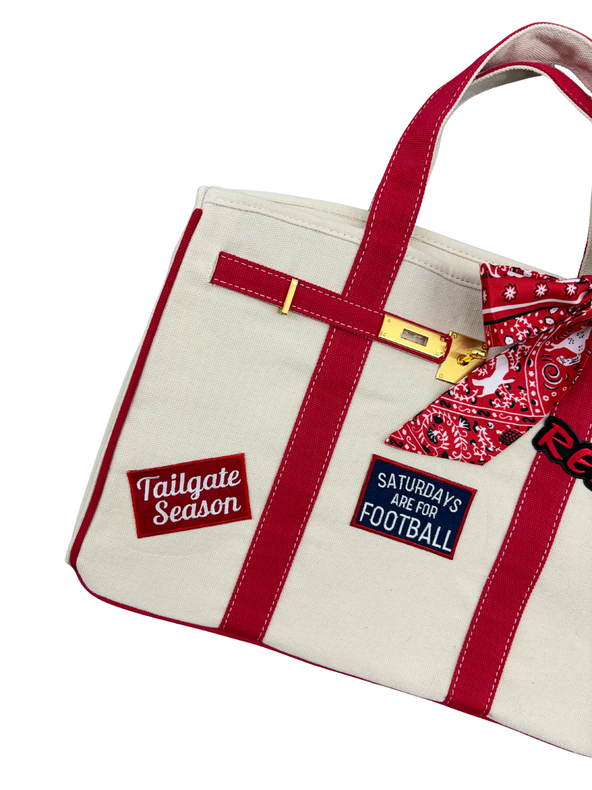 Detailed view of the left side of the Ole Miss canvas weekender tote bag showcasing embroidered Tailgate Season and Saturdays Are For Football iron on patches on beige canvas with red trim.