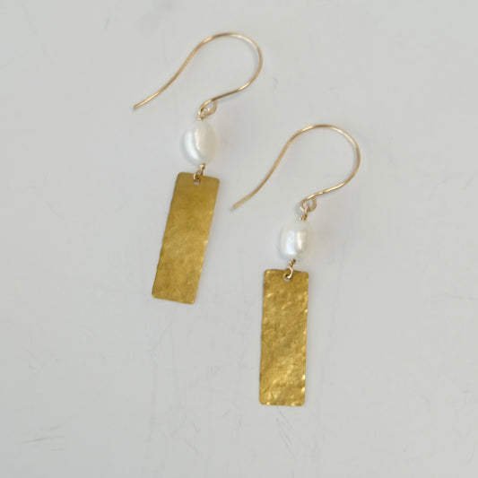 Pearl brass dangle earrings displayed on a light gray background