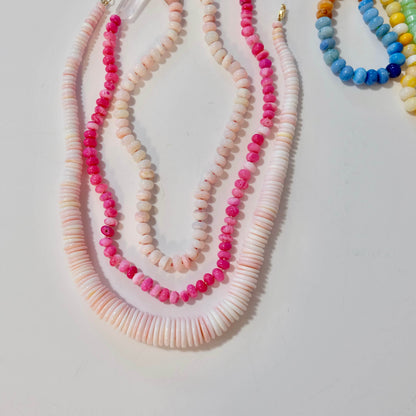 Pink conch shell bead necklace layered with colorful beaded necklaces