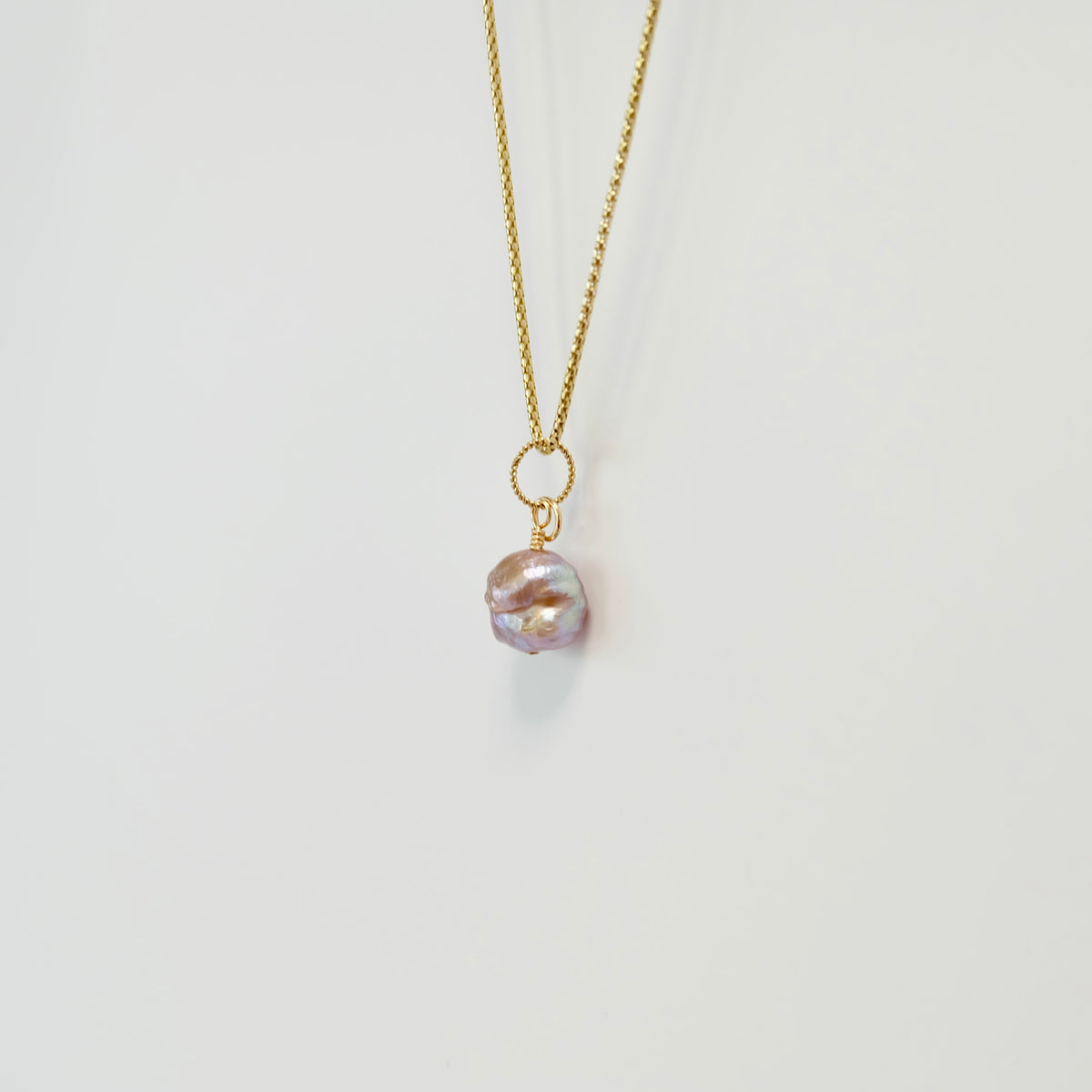 Close-up of a pink rosebud freshwater pearl with purple iridescence