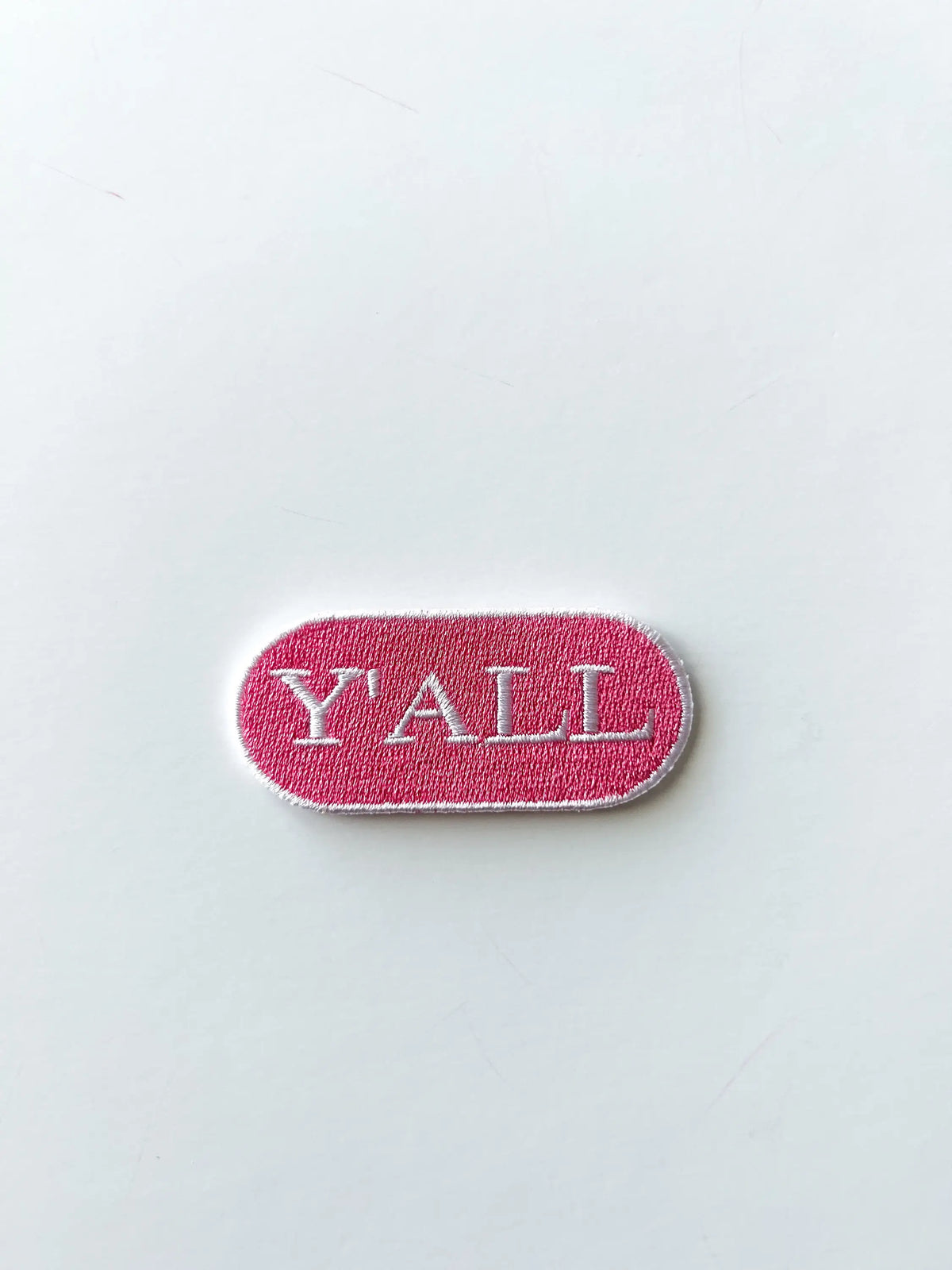 Pink Y'all iron-on patch for layering with other patches on a tote