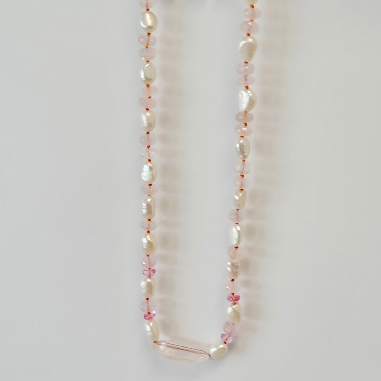 pink topaz, rose quartz, and pearl candy necklace elegantly knotted on silk, showcasing a delicate and vibrant design.