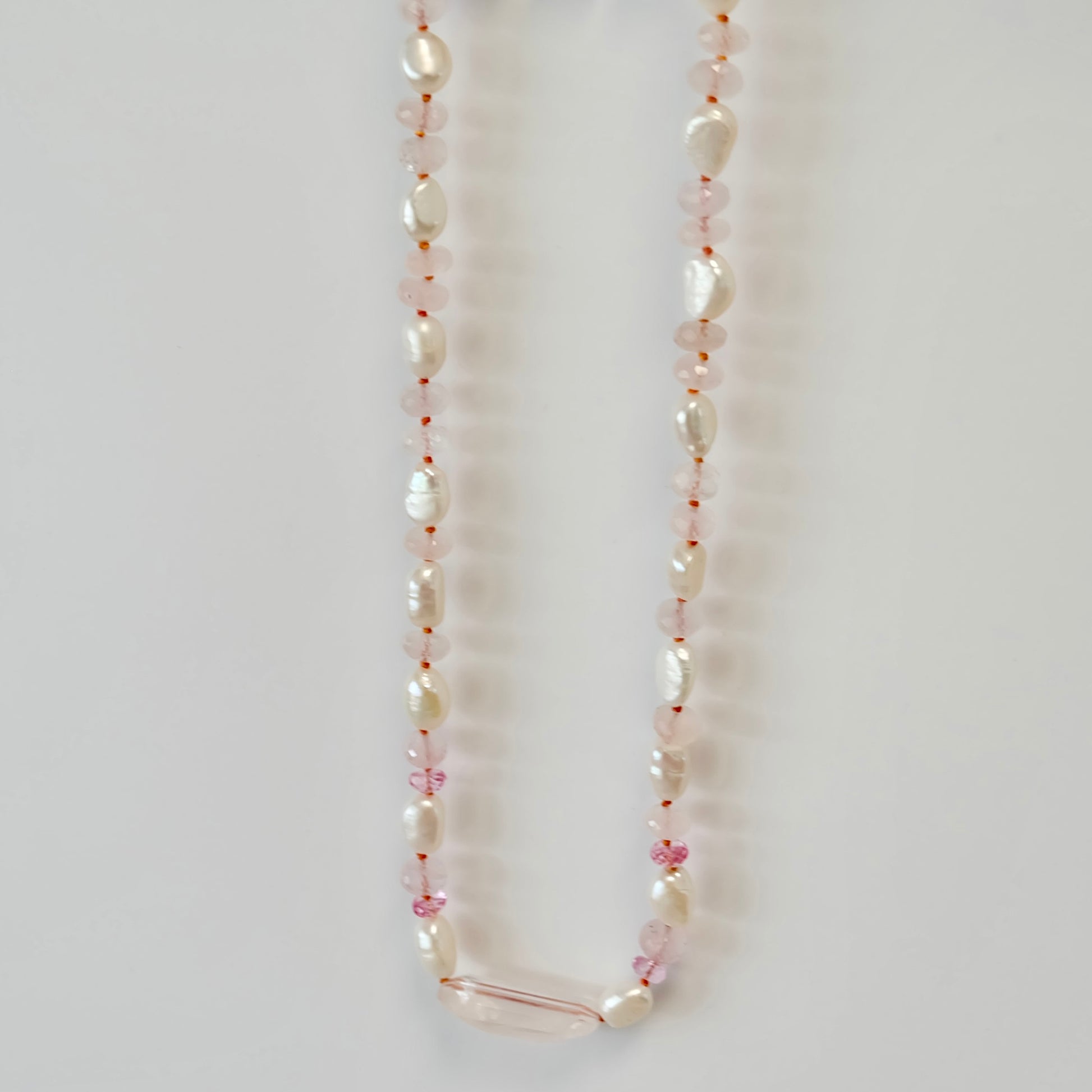 pink topaz, rose quartz, and pearl candy necklace elegantly knotted on silk, showcasing a delicate and vibrant design.