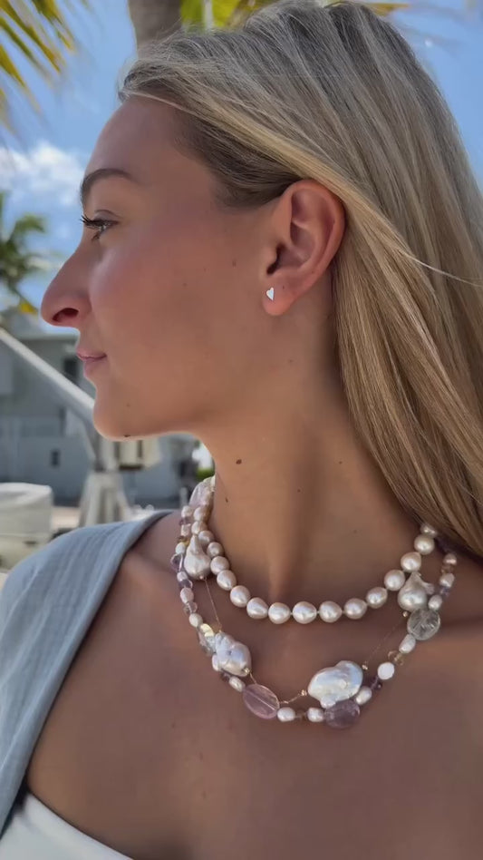 A collection of stacked necklaces featuring freshwater pearls