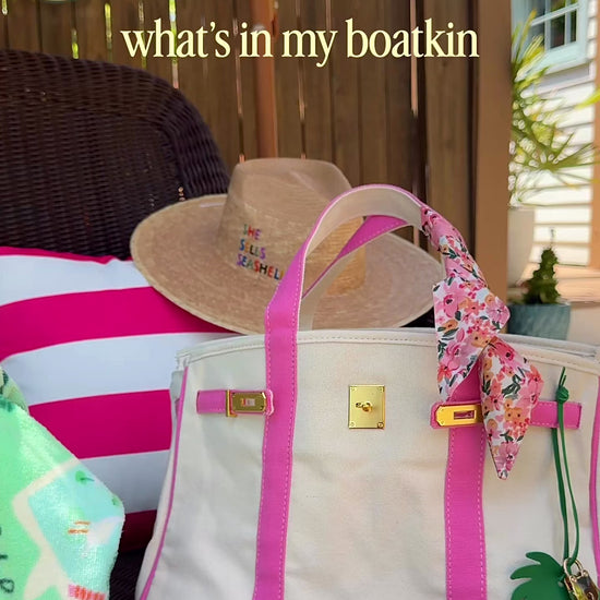 Boatkin canvas tote bag shown holding a 15-inch MacBook Air, sunglasses, makeup pouch, wallet, iPhone, and sunscreen, demonstrating interior capacity and everyday use.