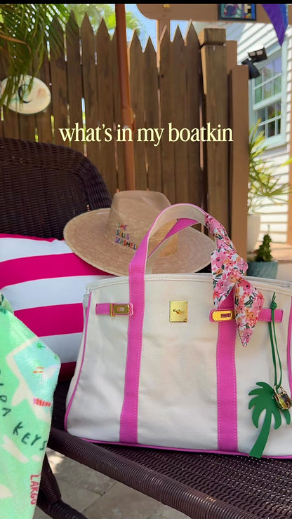 Boatkin canvas tote bag shown holding a 15-inch MacBook Air, sunglasses, makeup pouch, wallet, iPhone, and sunscreen, demonstrating interior capacity and everyday use.