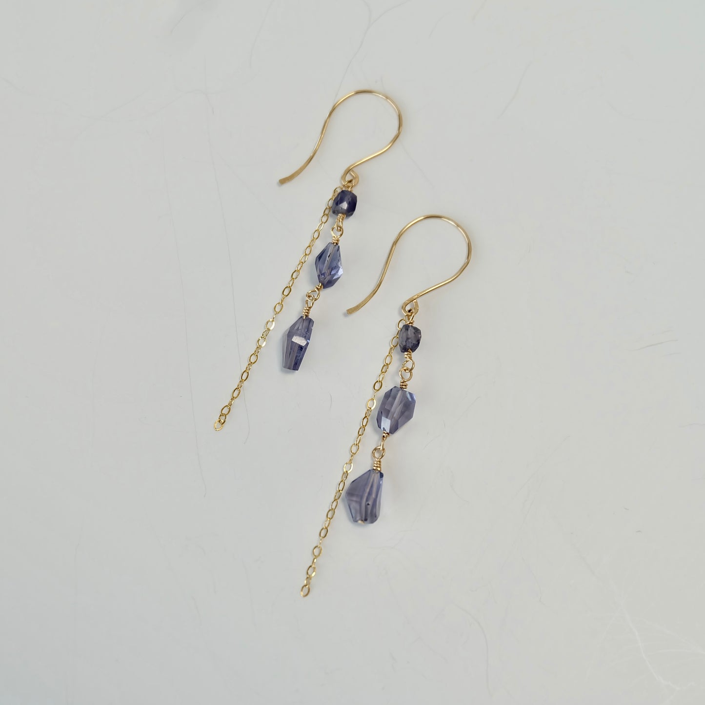 Purple iolite dangle earrings with beads on a light gray background