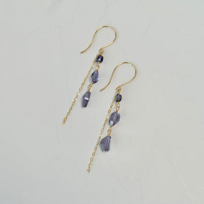 Purple iolite dangle earrings with beads on a light gray background