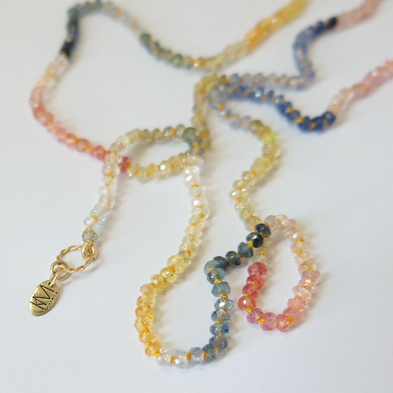 Close-up of the Rainbow Sapphire Necklace showcasing faceted sapphire beads hand-knotted on yellow silk thread.