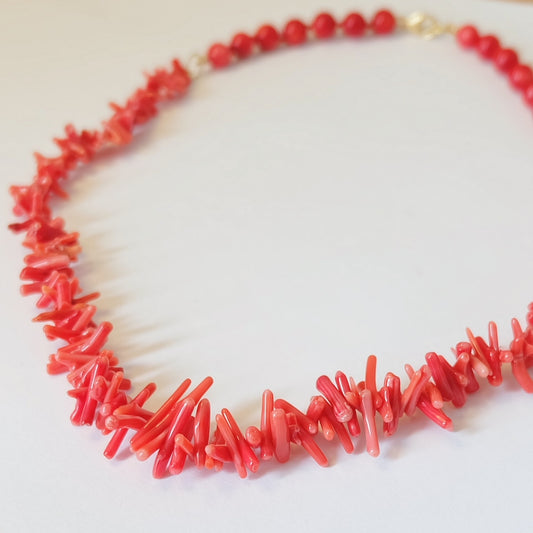 Close-up of red bamboo coral beads and sticks hand-knotted on red silk