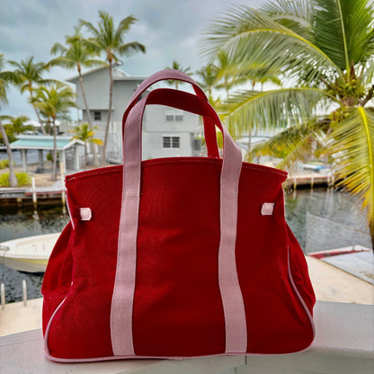 Back view of red and pink Boatkin tote bag on dock with palm trees and waterfront homes