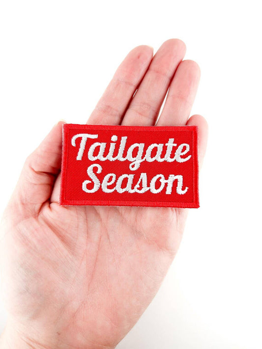 Red patch with 'Tailgate Season' text held in a hand against a white background