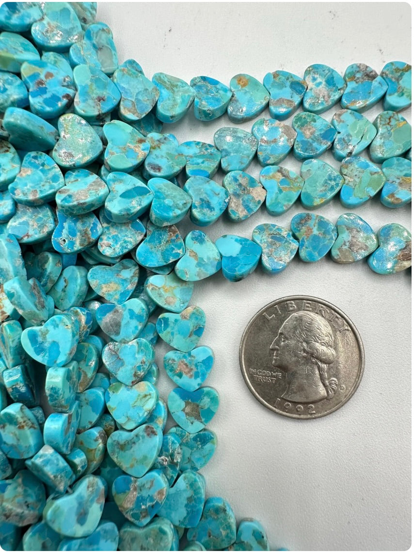 Robin's egg blue turquoise heart-shaped beads with a quarter for scale on a white background
