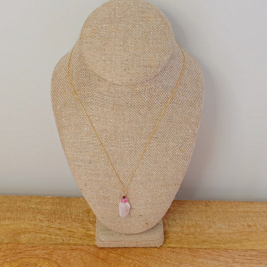 Close-up of rose quartz, pink topaz, and garnet charms on a dainty gold-filled necklace