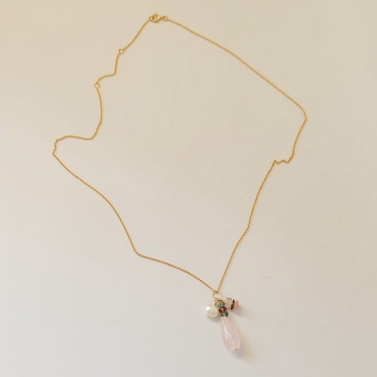 Close-up of rose quartz and tourmaline charms on a dainty gold-filled necklace
