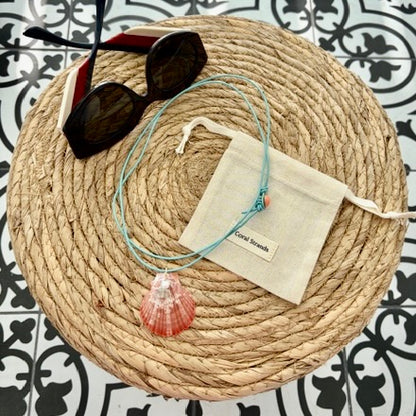 Sea shell pendant necklace with pink shell on woven mat
