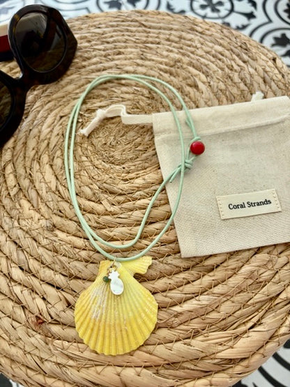 Sea shell pendant necklace with yellow fan-shaped shell and emerald on woven mat