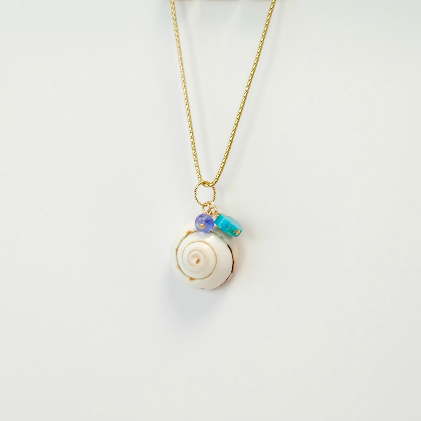 Turquoise tanzanite sea shell charm adorned with a heart crafted from Kingman turquoise, showcasing vibrant colors.