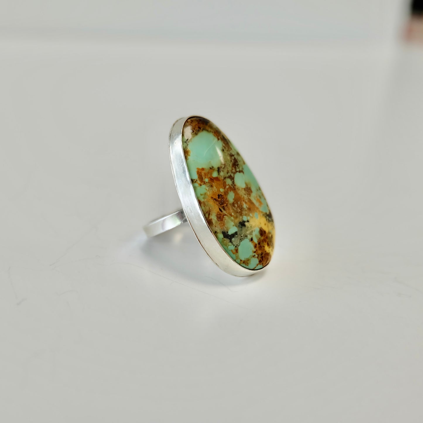 Silver ring with a a Stella blue turquoise cabochon on a light gray background