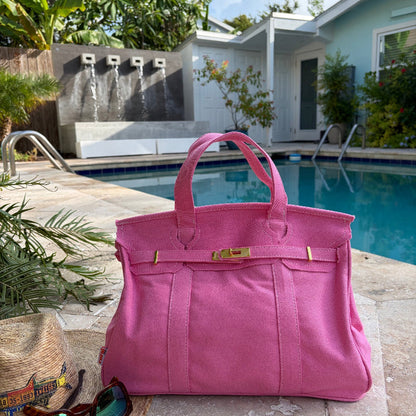 Solid pink Boatkin tote bag by a pool with a house and palm trees in the background.