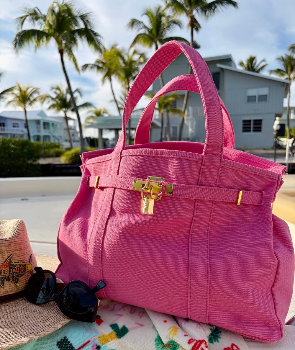 Solid pink Boatkin tote on a boat deck with palm trees and house in the background