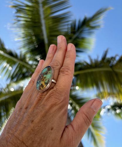 Model wearing Stella Blue turquoise ring, styled with a black dress for an elegant evening look.