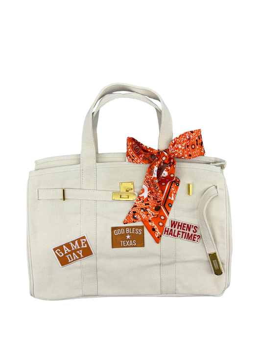 Ccream winter white Texas Longhorns college football tote bag featuring a bright orange bandana print twilly scarf tied to the handle and game day iron on patches.
